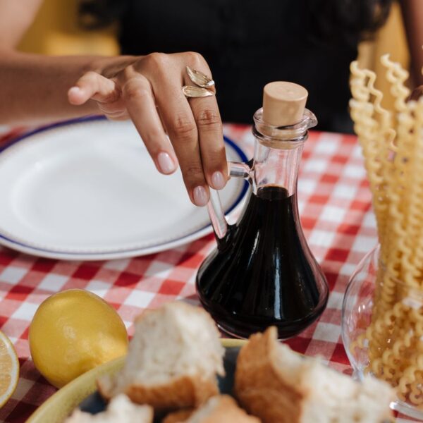 Balsamico A close-up of a hand reaching for vinegar at an Italian-themed table.