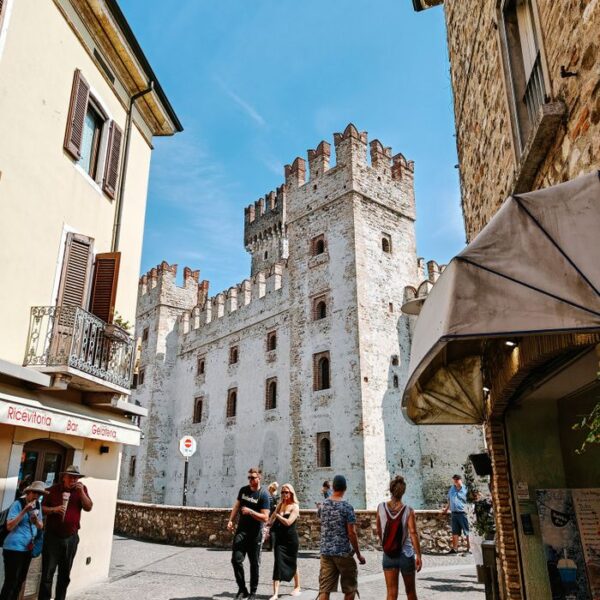 Sirmione Scenic view of Scaliger Castle in Sirmione with tourists exploring the charming streets.