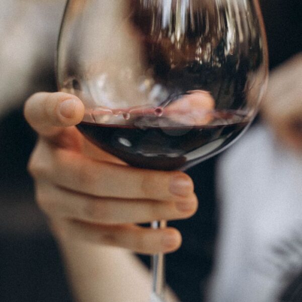 Glass of Wine Close-up shot of hand holding a glass of red wine, showcasing elegance and luxury.