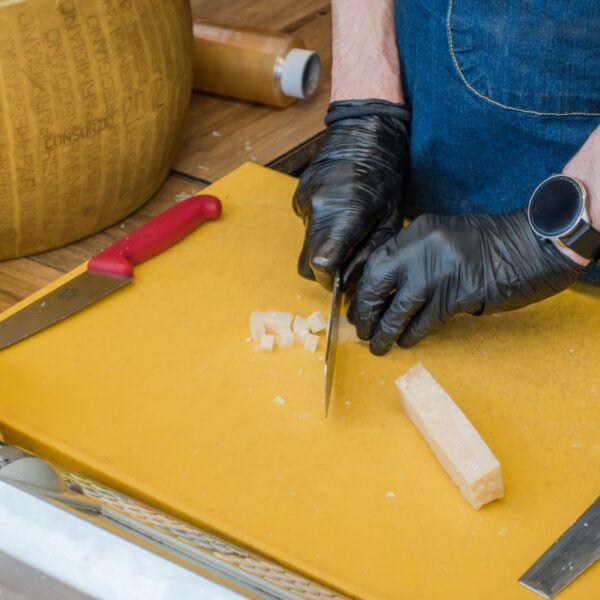 Parmigiano Reggiano Person cutting Parmigiano-Reggiano cheese on a yellow board with various tools. Perfect for culinary themes.