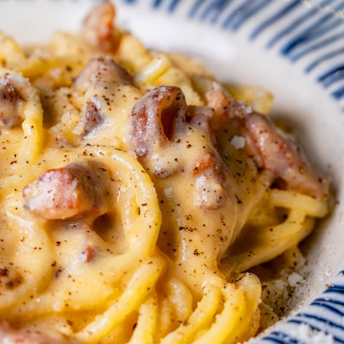 Close-up of creamy spaghetti carbonara with pancetta in a stylish ceramic dish.