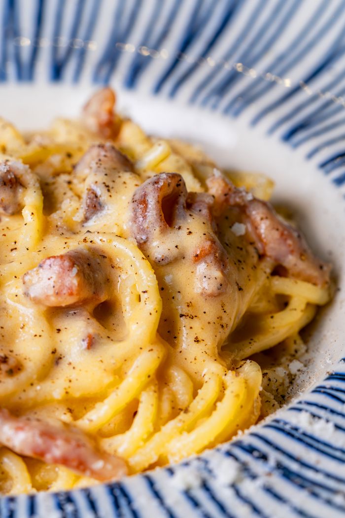 Close-up of creamy spaghetti carbonara with pancetta in a stylish ceramic dish.