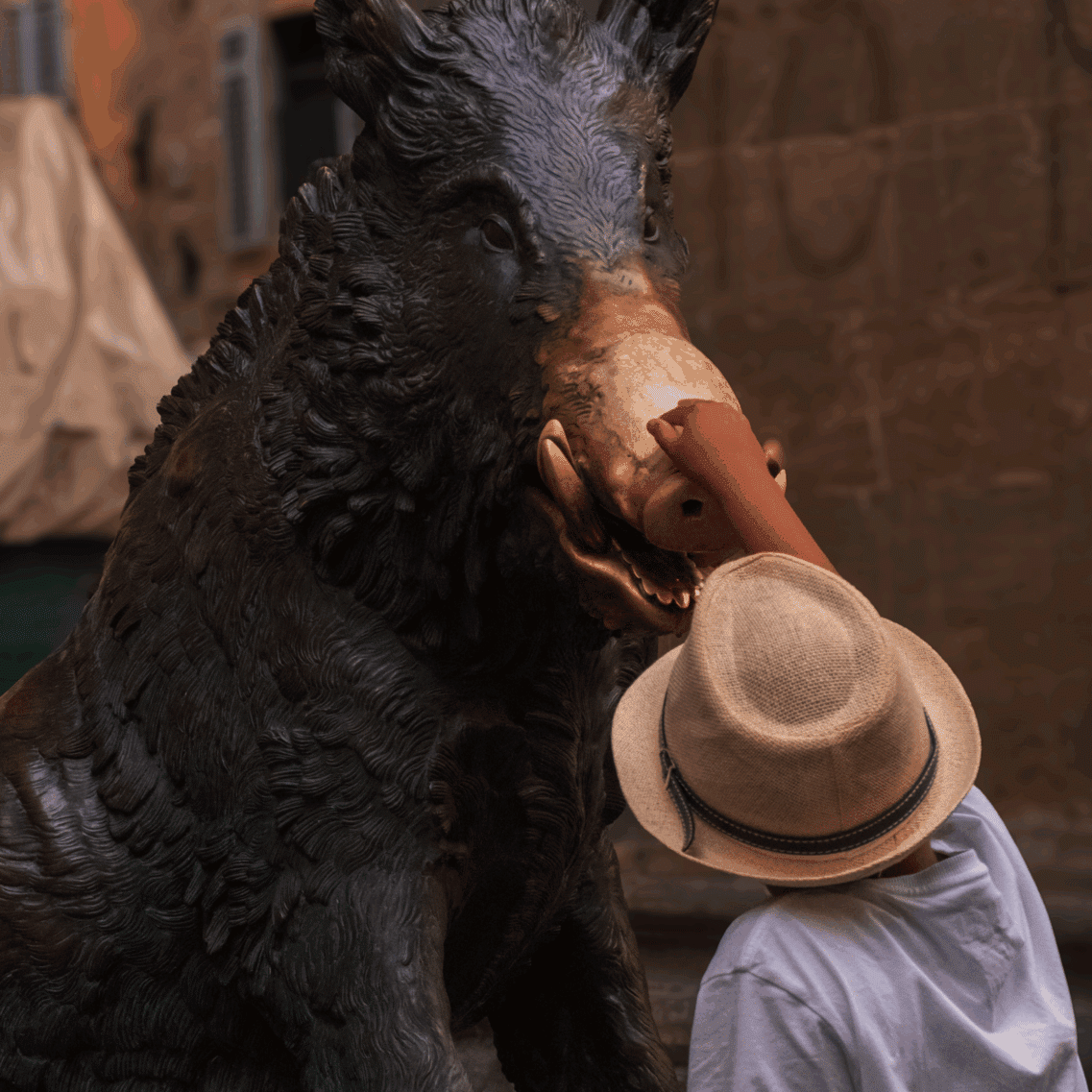 A child touches the Florence boar statue's snout, symbolizing good fortune.
