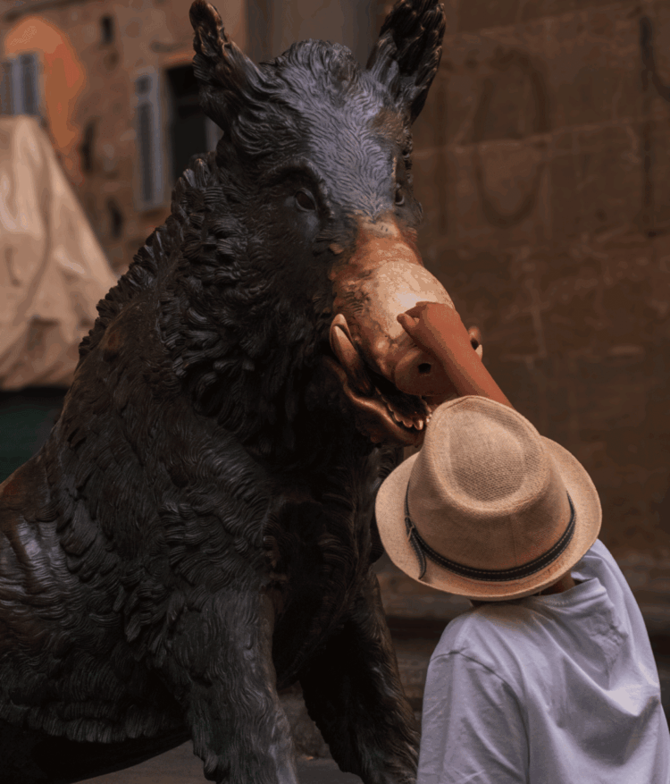A child touches the Florence boar statue's snout, symbolizing good fortune.