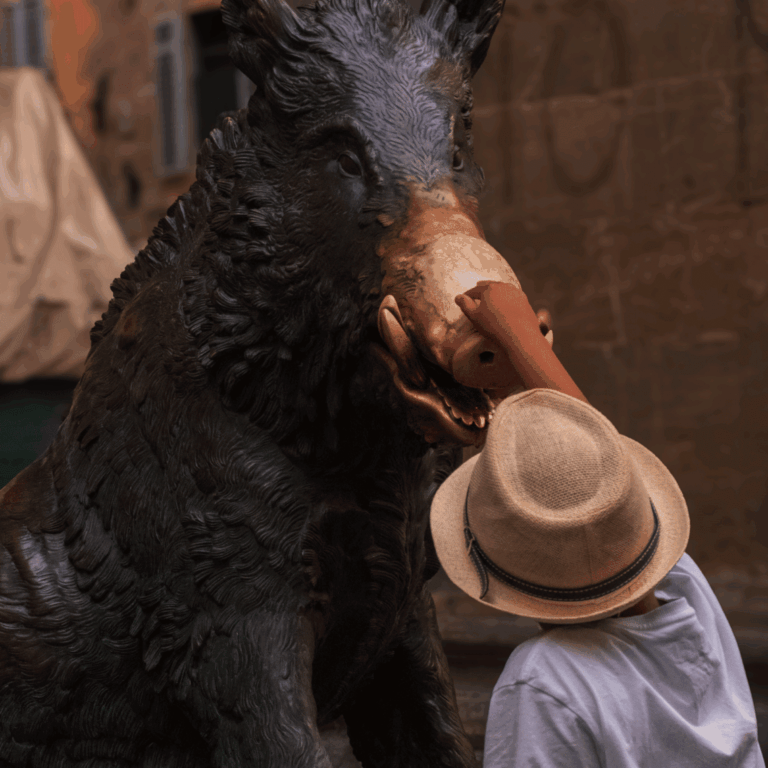 A child touches the Florence boar statue's snout, symbolizing good fortune.