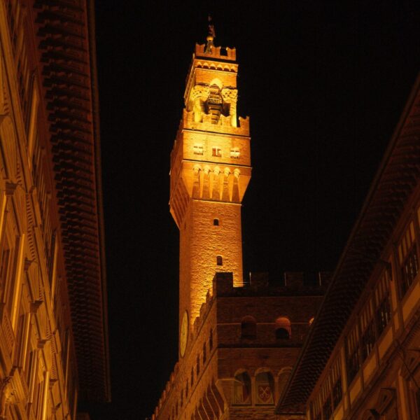 Dramatic night view of the illuminated Palazzo Vecchio Tower in Florence, Italy.