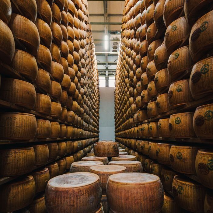 Rows of Parmesan cheese wheels aging in an Emilia-Romagna warehouse.