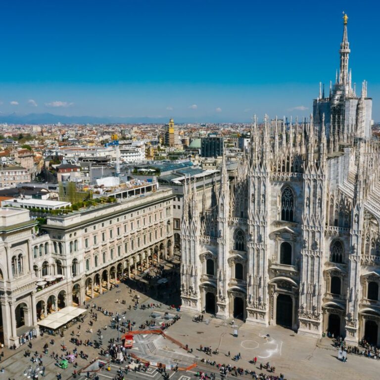 Stunning aerial shot of Milan Cathedral in Italy with bustling cityscape under a clear blue sky.