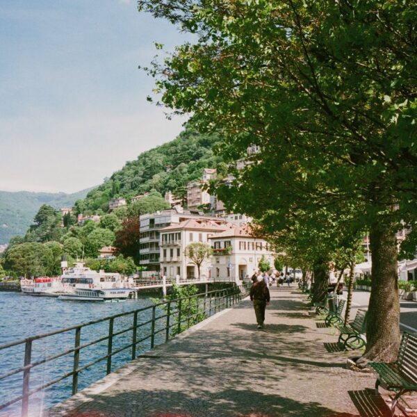 Como Beautiful lakeside promenade in Como, Lombardy, Italy with lush greenery and clear blue skies.